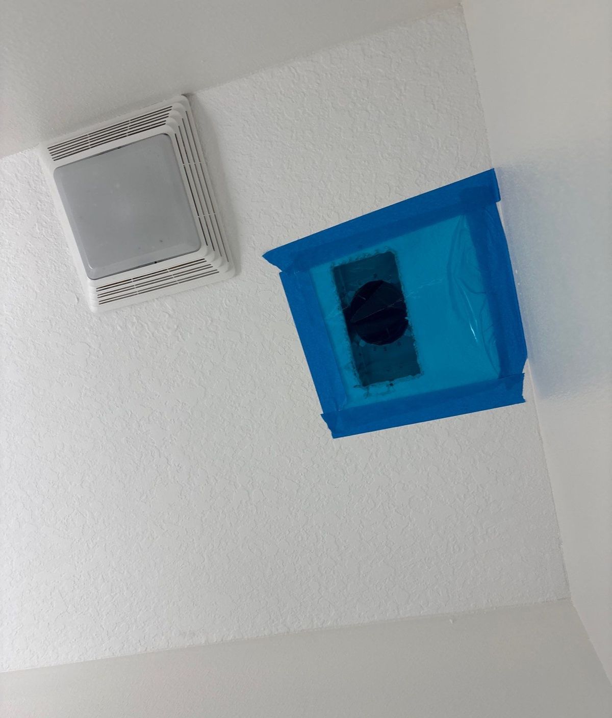 Ceiling supply register masked off with plastic and tape during duct tear-out