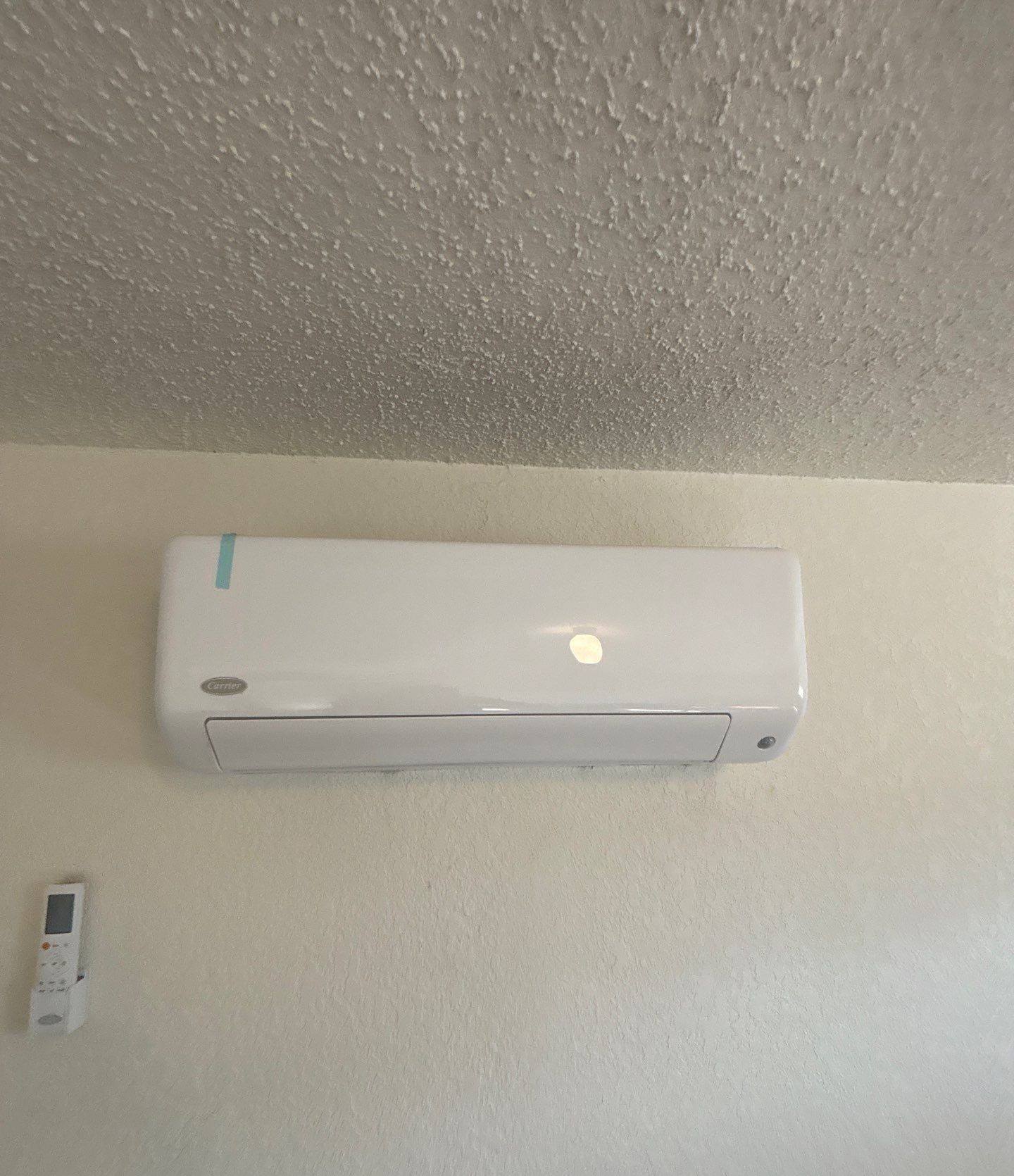Finished wall-mounted mini-split head with its remote in a Riverview home