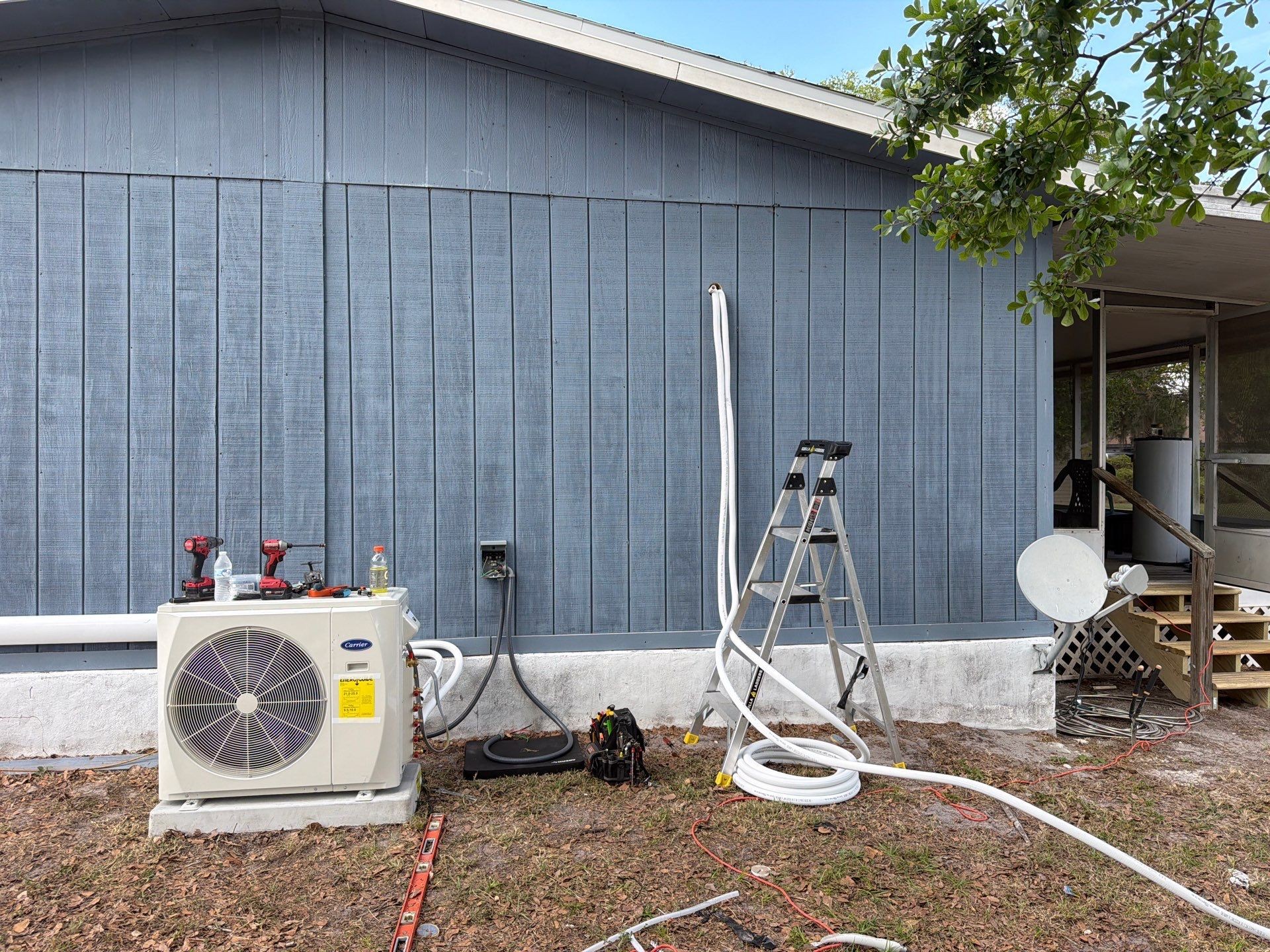Refrigerant line-hide being installed along the exterior wall of a Riverview home