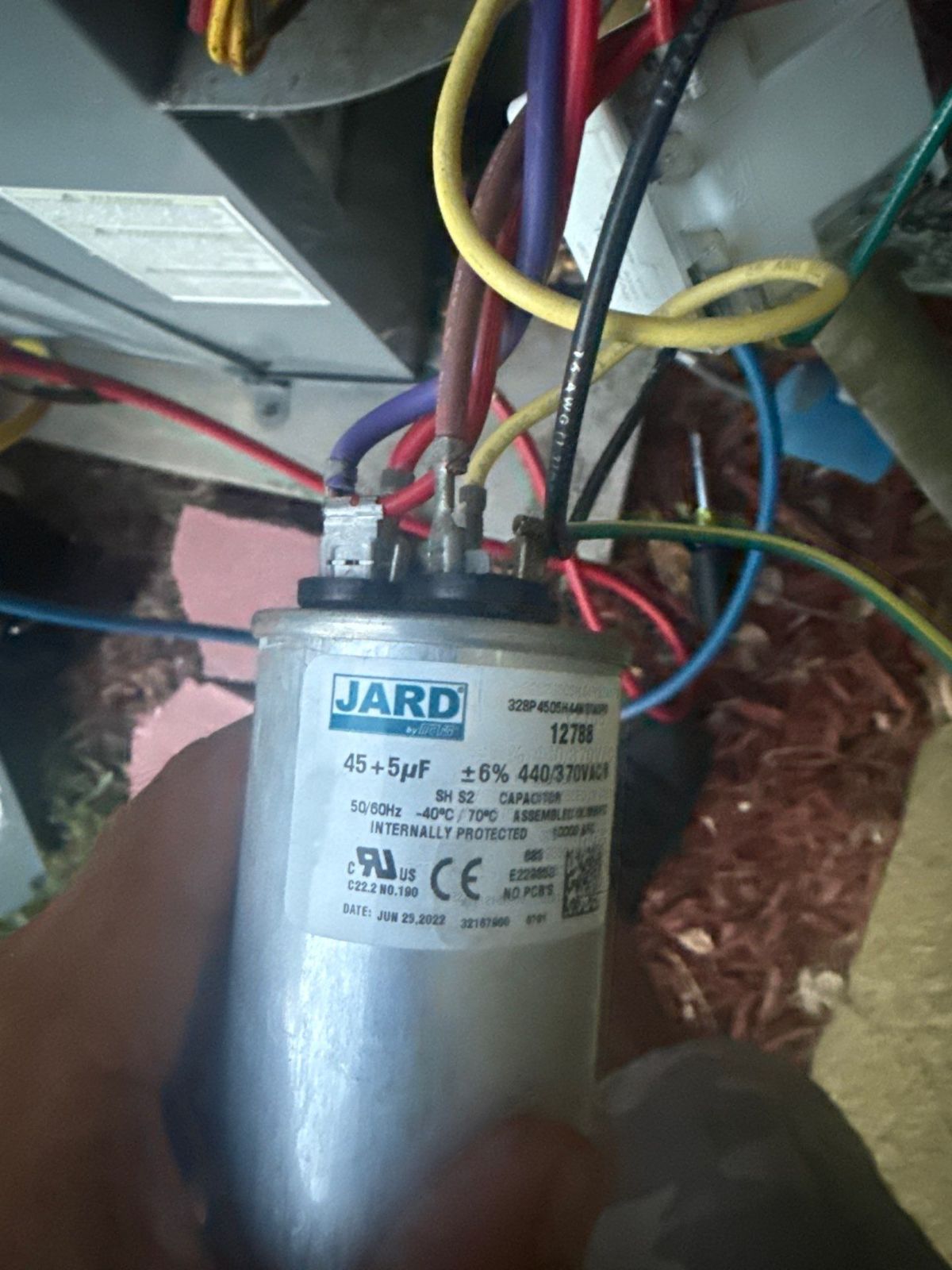 Technician holding the capacitor from the old outdoor unit during diagnosis
