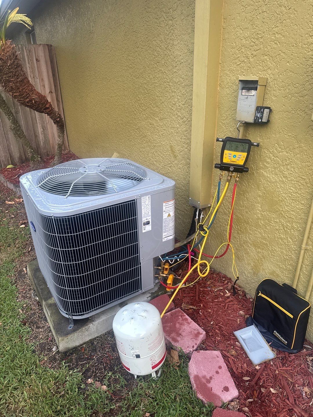 New heat pump outdoor unit on gauges at startup beside a Land O' Lakes home
