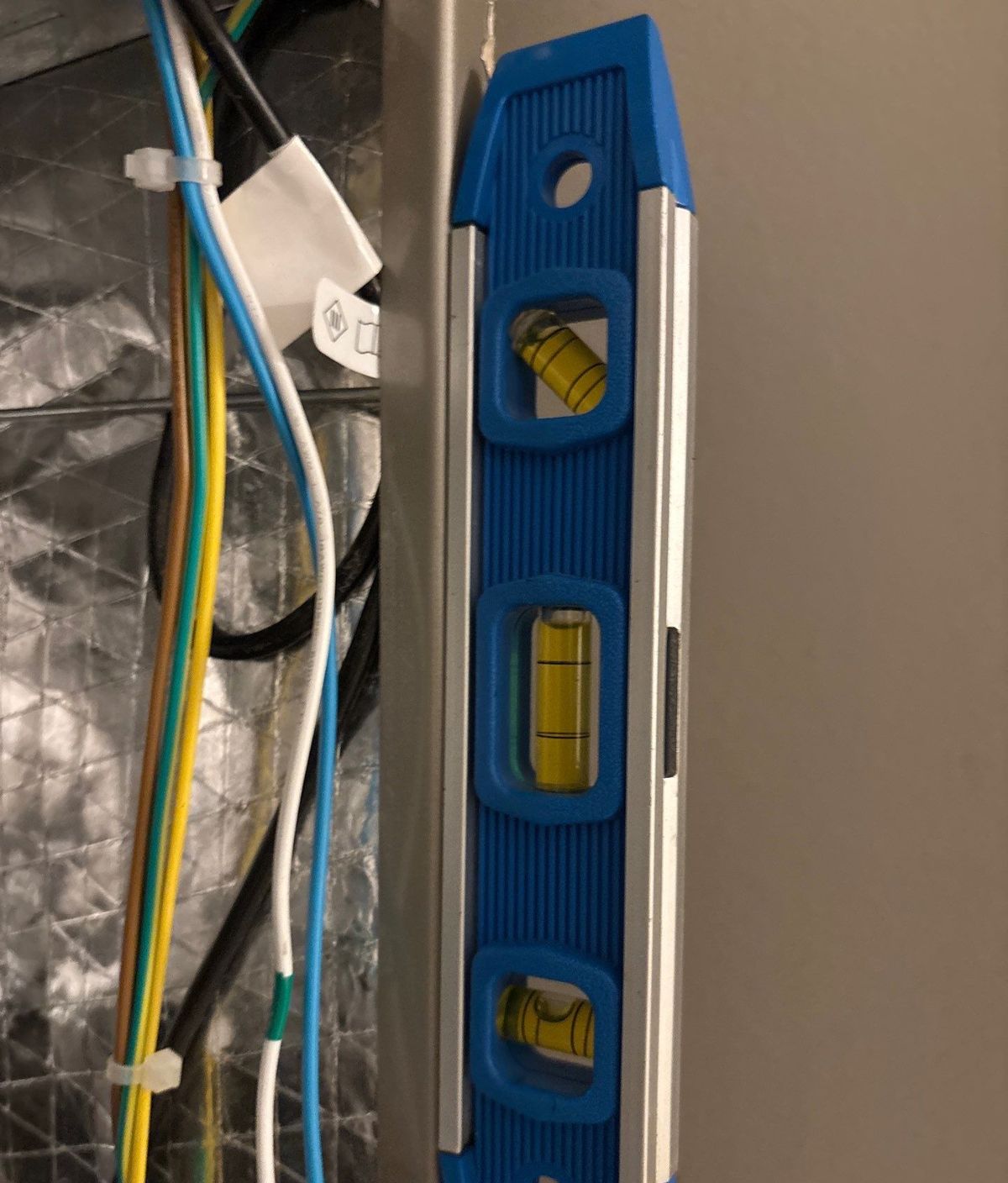 Technician leveling a new vertical air handler in its closet