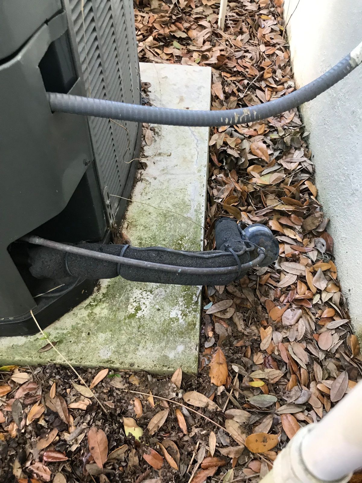 Old outdoor unit on a worn pad beside a New Tampa home