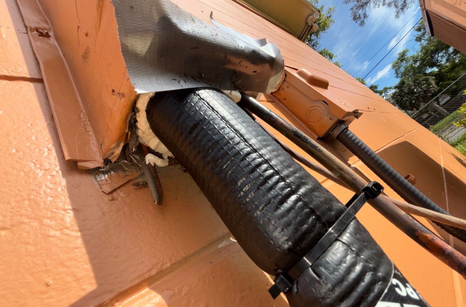 Insulated refrigerant line set entering the wall of a Tampa home